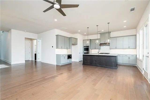 a large white kitchen with kitchen island a sink stainless steel appliances and a fireplace