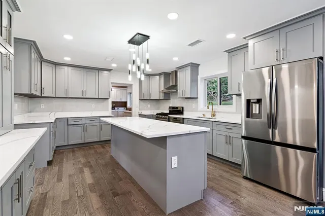 a kitchen with kitchen island granite countertop a sink refrigerator and cabinets