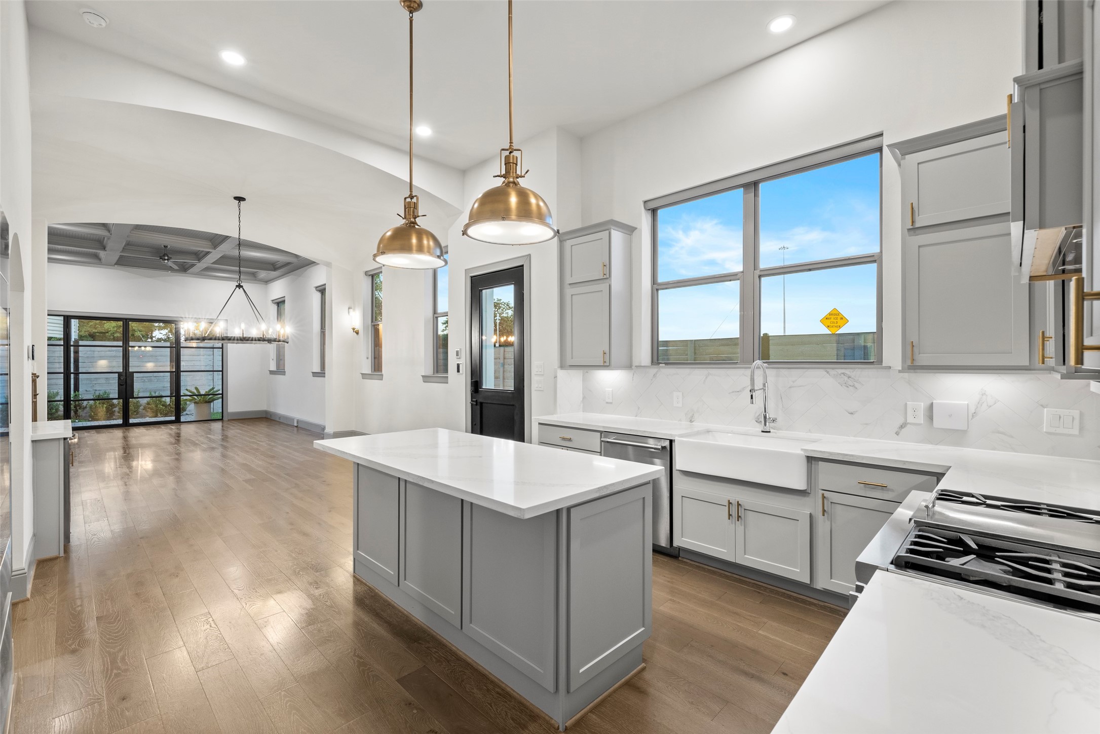 a large kitchen with kitchen island a sink appliances wooden floor and a view of living room