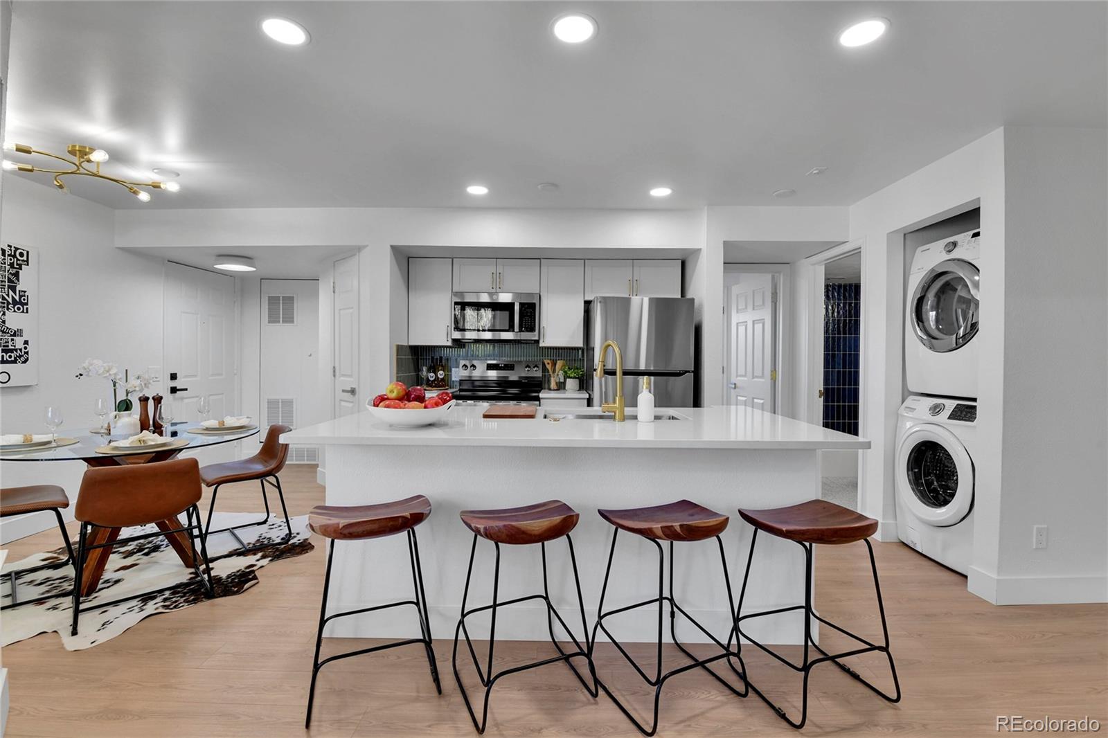 4878 East Kentucky Avenue, Unit E Denver, CO 80246 - Photo 5 of 19 a kitchen with stainless steel appliances kitchen island granite countertop a dining table chairs and a refrigerator