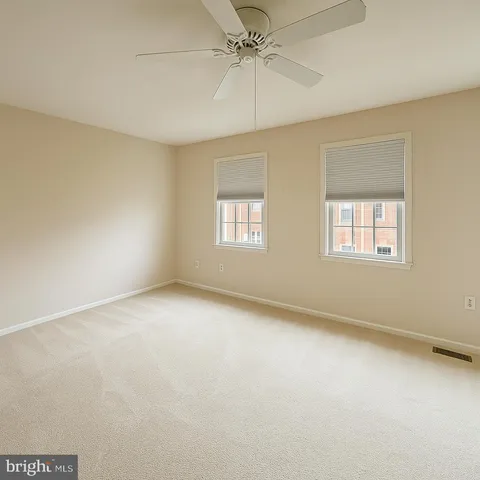 an empty room with windows and ceiling fan