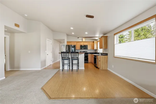 a kitchen with stainless steel appliances a dining table chairs and refrigerator