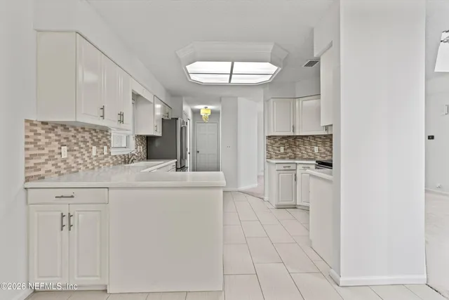 a kitchen with white cabinets and window