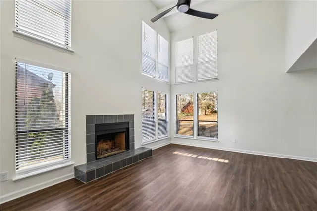 an empty room with wooden floor fireplace and windows