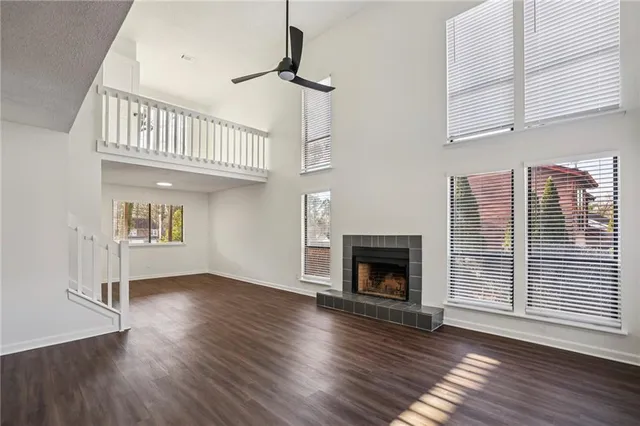 a view of an empty room with wooden floor fireplace and a window