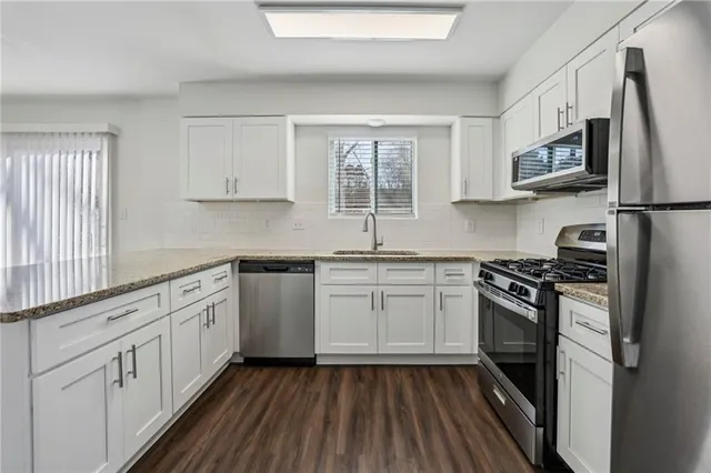 a kitchen with stainless steel appliances granite countertop a stove a sink and a refrigerator