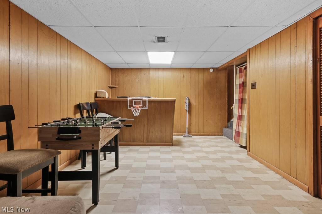 611 Herbert Road Akron, OH 44312 - Photo 24 of 30 Recreation room featuring wood paneling, checkered tile flooring, a built-in bar, and a drop ceiling with recessed lighting