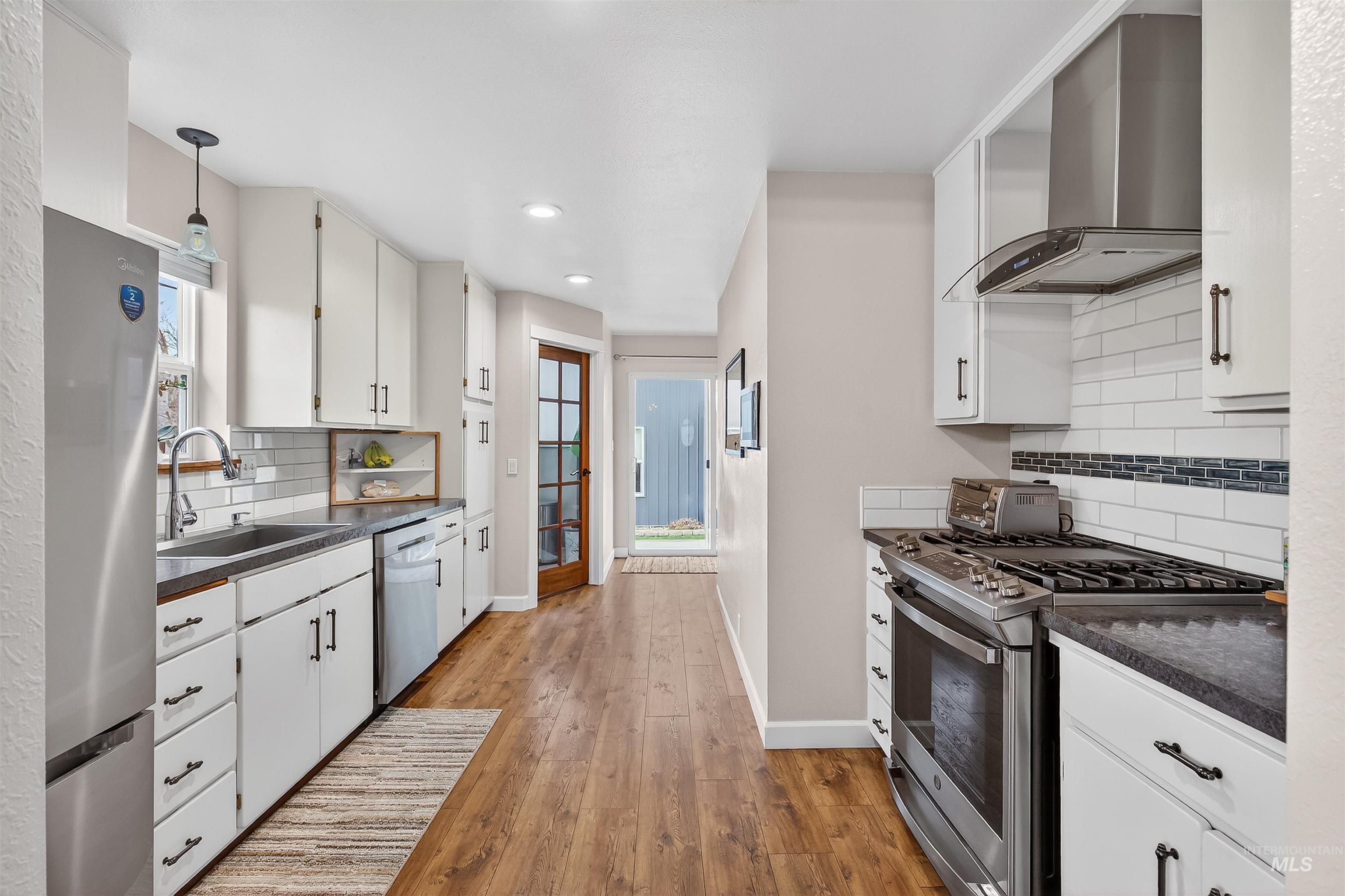 716 Chestnut Street Clarkston, WA 99403 - Photo 16 of 49 Kitchen with dark countertops, stainless steel appliances, white cabinets, and light wood finished floors