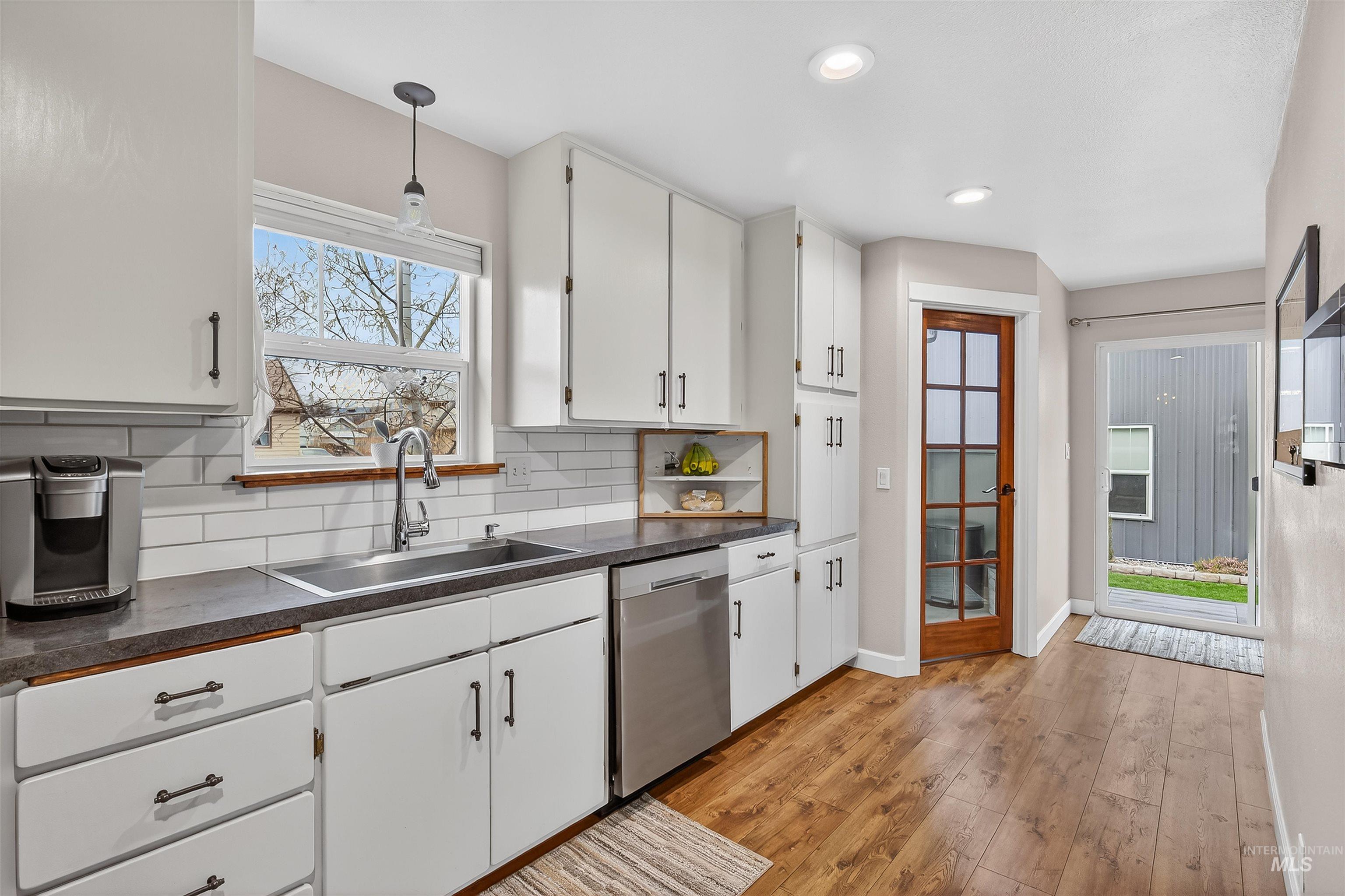 716 Chestnut Street Clarkston, WA 99403 - Photo 20 of 49 Kitchen featuring dark countertops, white cabinets, light wood-type flooring, dishwasher, and tasteful backsplash