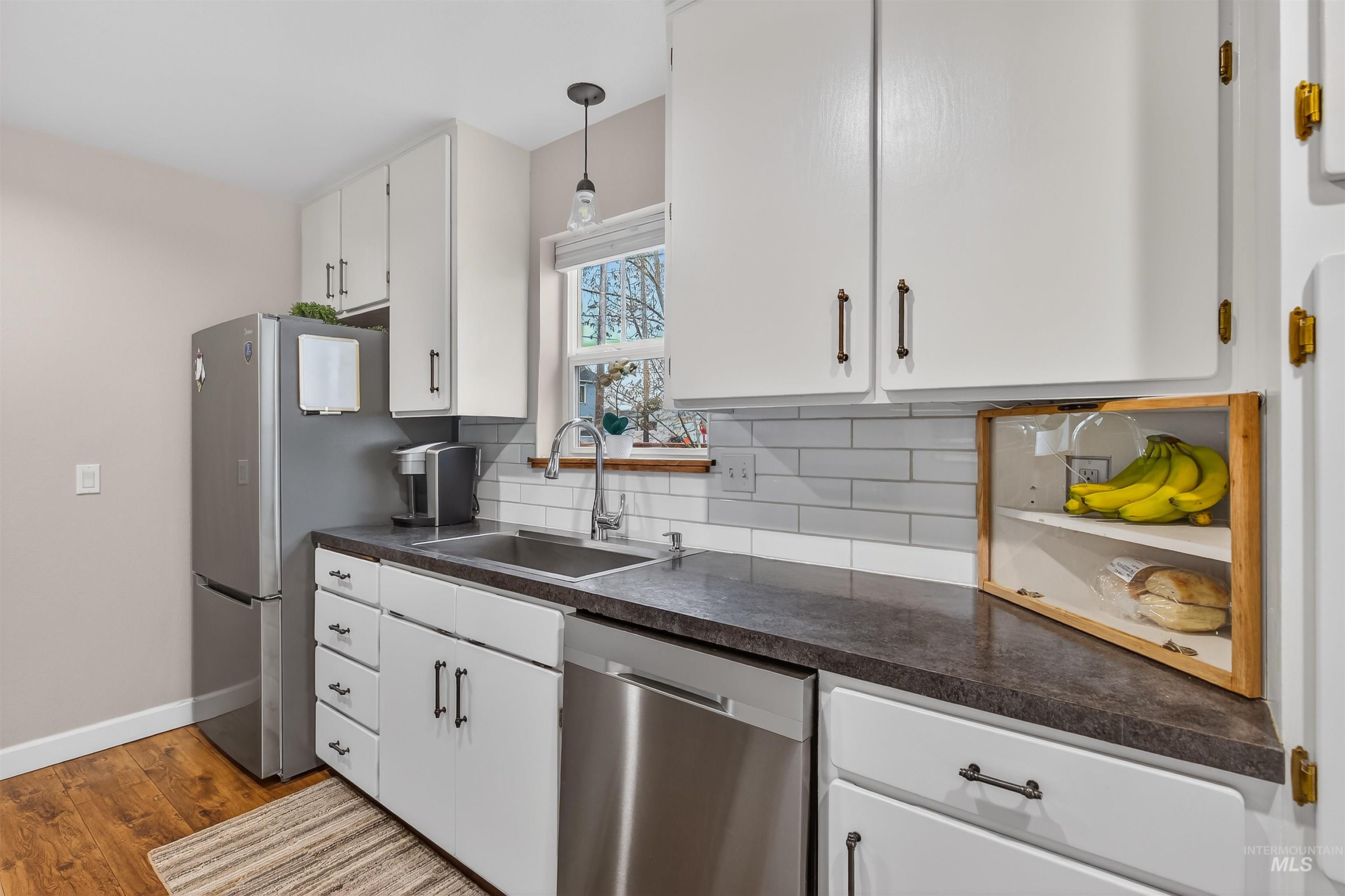 716 Chestnut Street Clarkston, WA 99403 - Photo 41 of 49 Kitchen featuring white cabinetry, dark countertops, dishwasher, backsplash, and dark wood-style floors