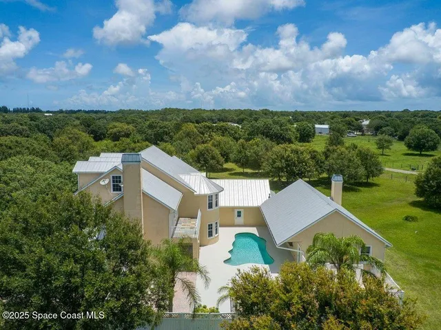 an aerial view of a house with a yard and lake view in back