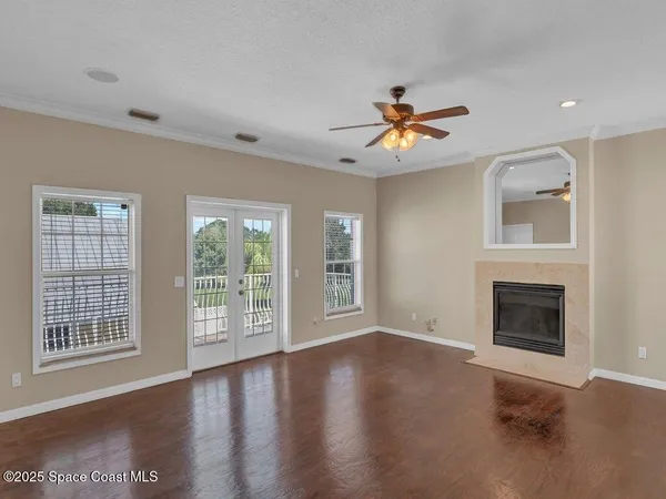 a view of an empty room with window and wooden floor