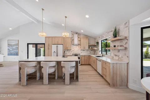 a kitchen with stainless steel appliances a white table chairs and a refrigerator