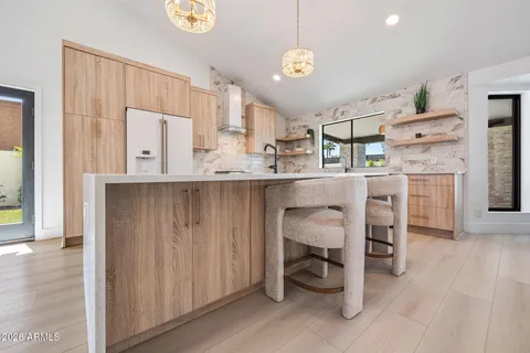 a view of kitchen with stainless steel appliances granite countertop a refrigerator a oven a dining table and chairs with wooden floor