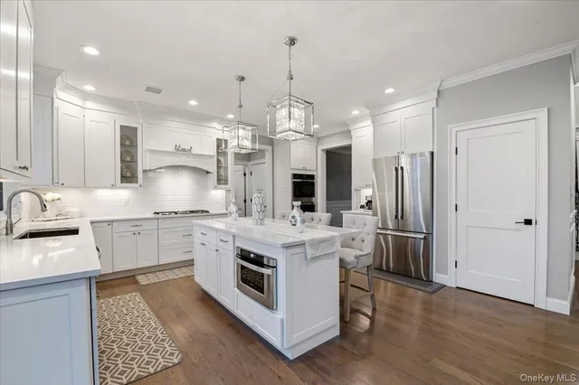 a kitchen that has a lot of white cabinets and stainless steel appliances