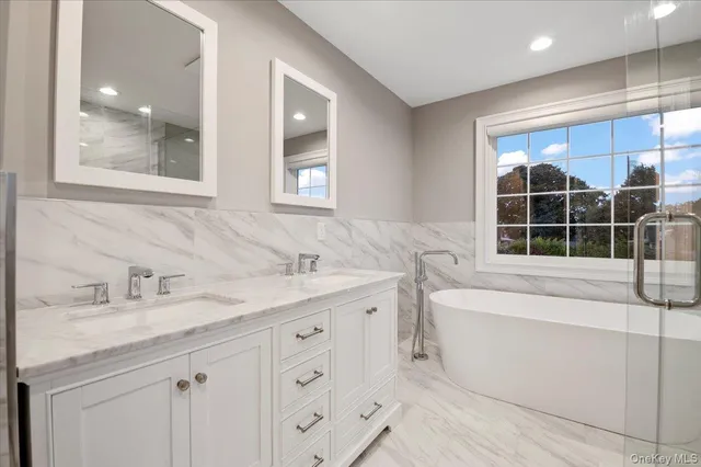 a bathroom with a tub sink and mirror