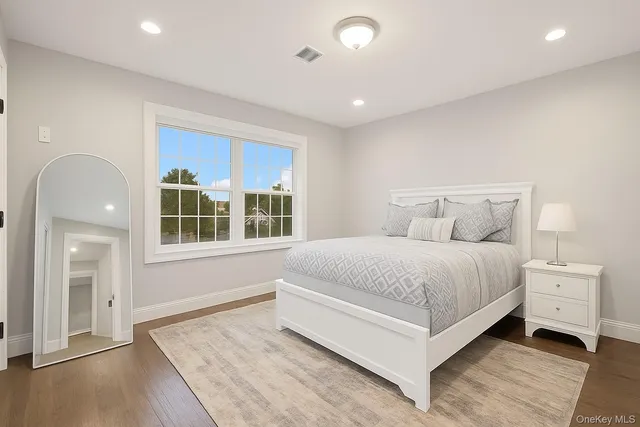 a spacious bedroom with a bed and wooden floor