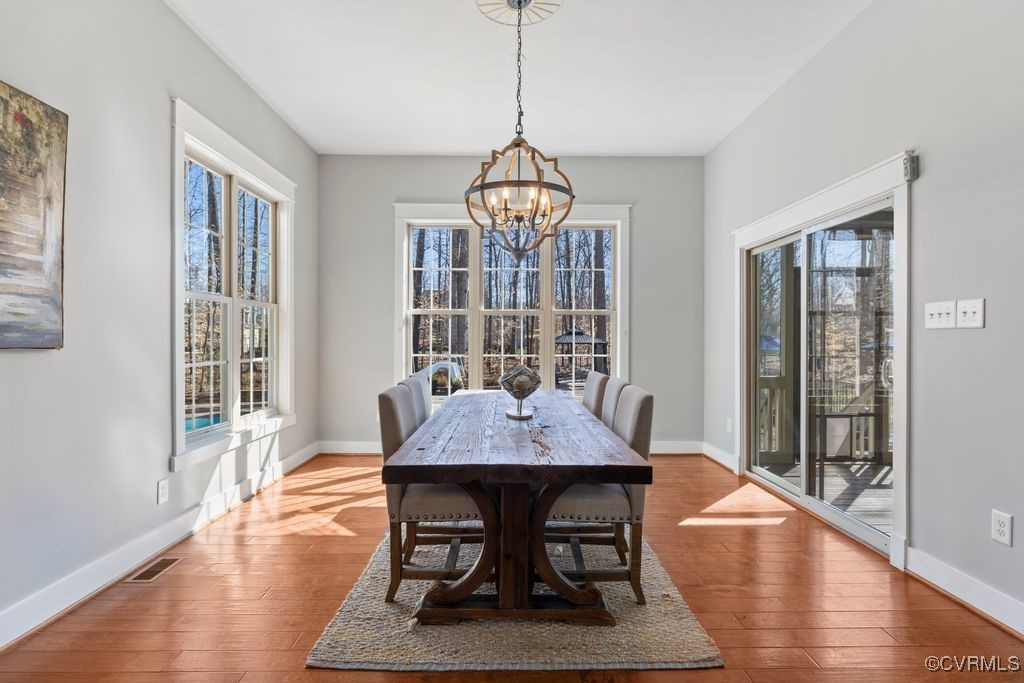 14106 Old Fort Drive Midlothian, VA 23113 - Photo 12 of 47 a dining room with wooden floor a chandelier a wooden table and chairs