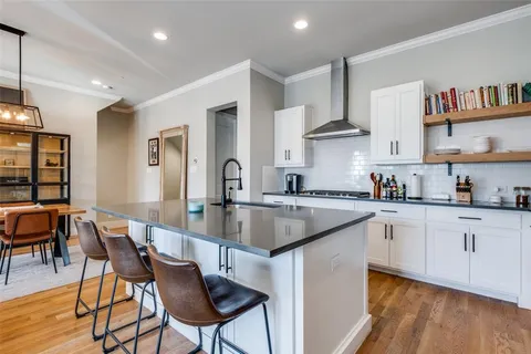 a kitchen with stainless steel appliances granite countertop a stove top oven a sink a dining table and chairs