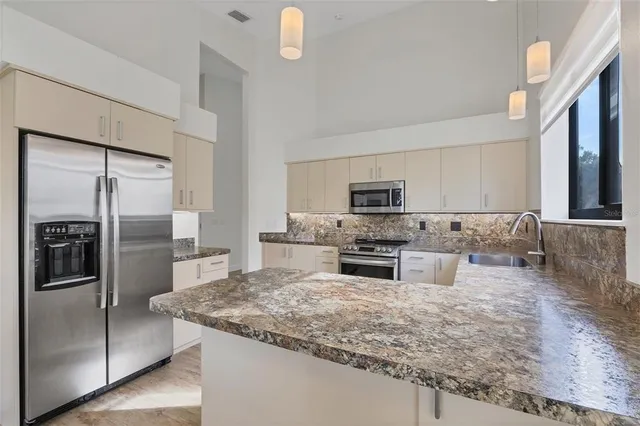 a view of an empty room with window and chandelier fan