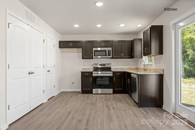 a kitchen with stainless steel appliances granite countertop a refrigerator stove top oven and sink