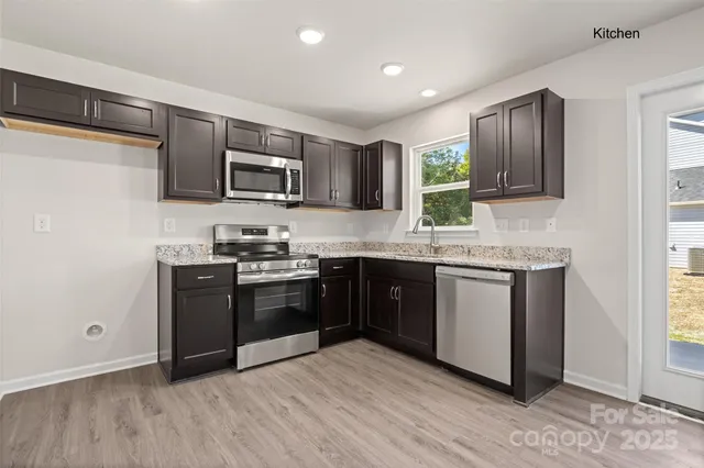 a kitchen with stainless steel appliances granite countertop a stove a sink and a microwave