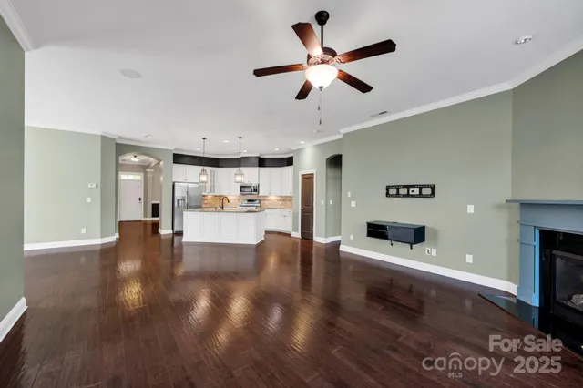 a view of a kitchen with furniture a ceiling fan and wooden floor