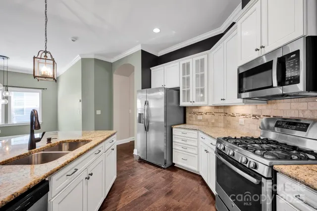 a kitchen with stainless steel appliances granite countertop a stove a sink dishwasher a refrigerator a microwave oven with white cabinets