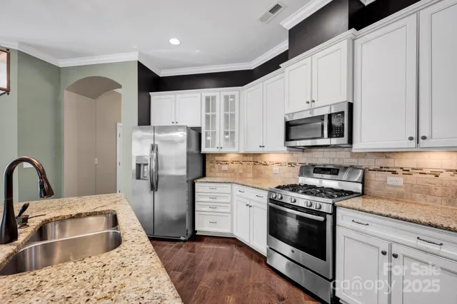 a kitchen with stainless steel appliances kitchen island granite countertop a refrigerator stove and sink