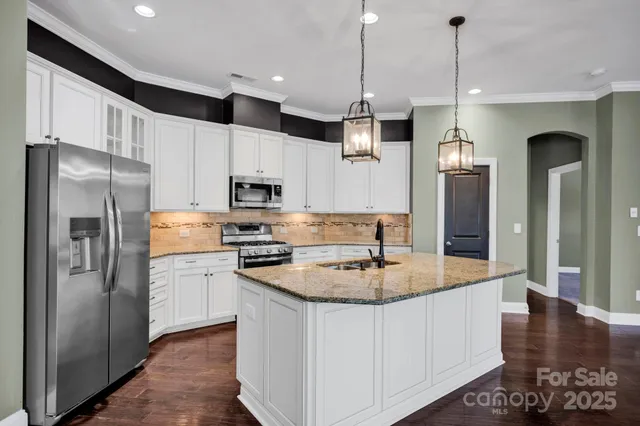 a kitchen with stainless steel appliances granite countertop a refrigerator a stove and a sink with wooden floor