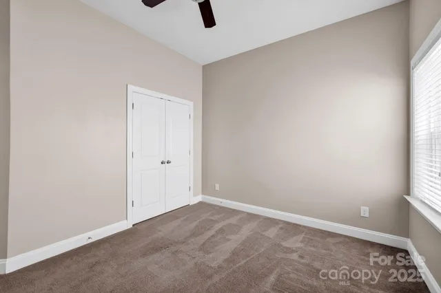 an empty room with a window and a ceiling fan