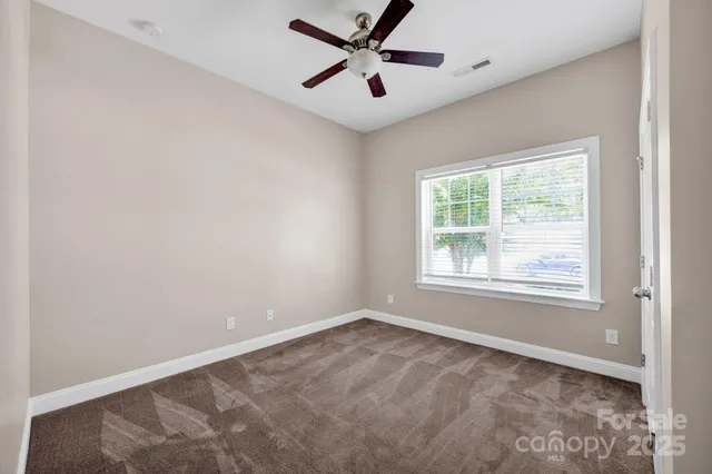 an empty room with a window and a fan