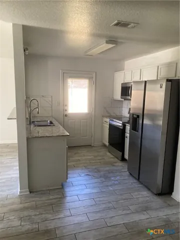 a kitchen with granite countertop a refrigerator sink and stove