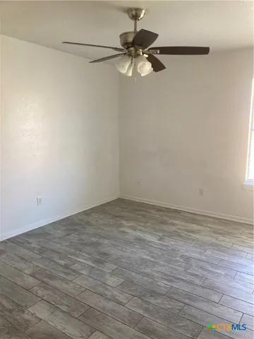 a view of a room with wooden floor and a ceiling fan