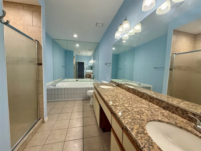 a bathroom with a granite countertop toilet sink and mirror