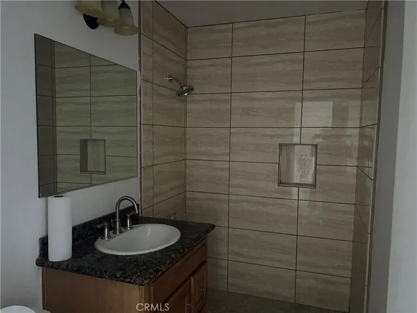 a bathroom with a granite countertop sink a mirror and shower