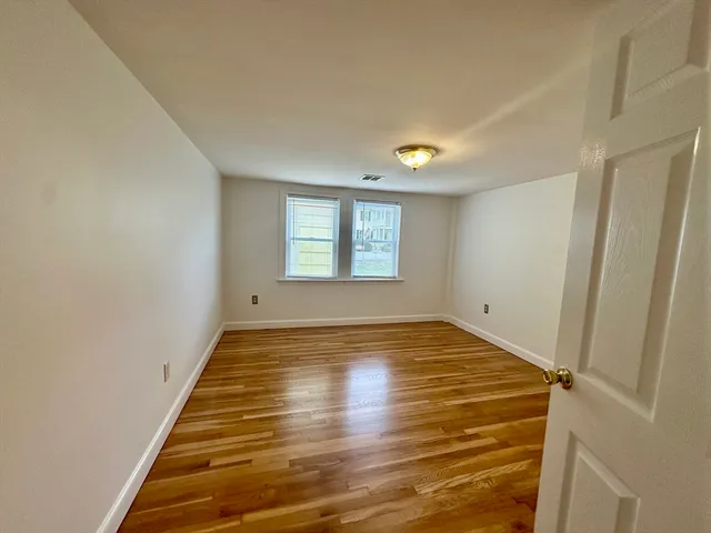 a view of empty room with window and wooden floor