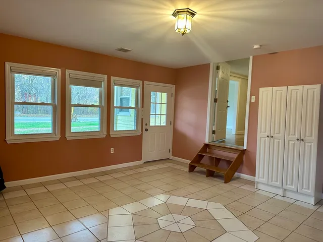 an empty room with chandelier fan and windows