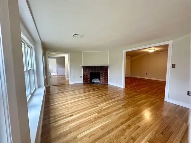 an empty room with wooden floor and fireplace