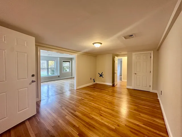 a view of an empty room with window and wooden floor