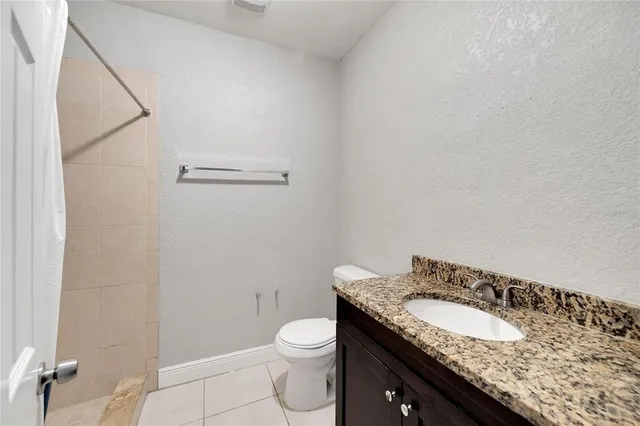 a bathroom with a granite countertop sink a toilet and a mirror