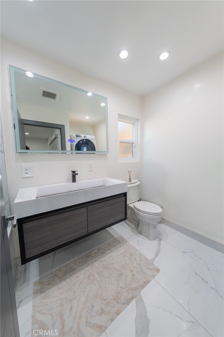 7719 Rhodes Avenue North Hollywood, CA 91605 - Photo 15 of 16 a spacious bathroom with a double vanity sink a toilet and a mirror