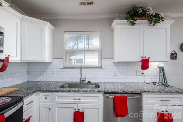 a kitchen with granite countertop a sink stove and cabinets