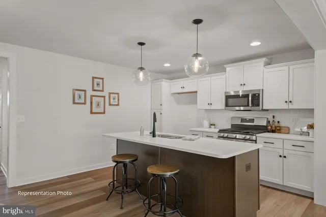 a kitchen with granite countertop a sink cabinets and wooden floor