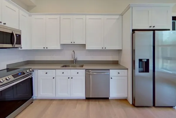 a kitchen with granite countertop white cabinets and stainless steel appliances