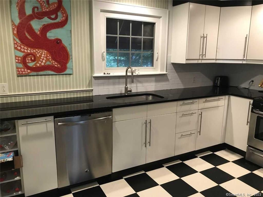 39 Masons Island Road Stonington, CT 06355 - Photo 4 of 16 a kitchen with granite countertop white cabinets and black appliances