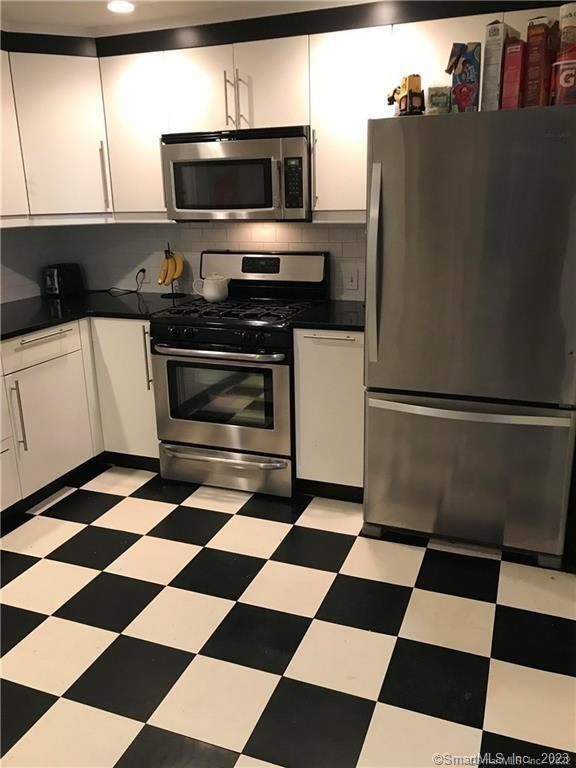 39 Masons Island Road Stonington, CT 06355 - Photo 6 of 16 a kitchen with a checkered floor and white cabinets