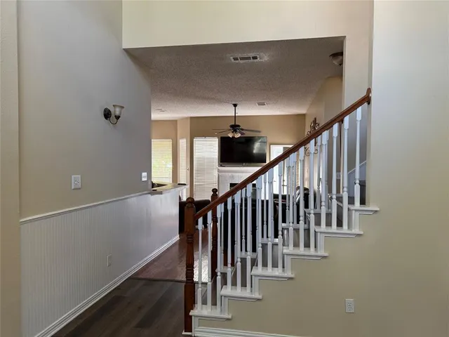 a view of staircase with wooden floor and fan
