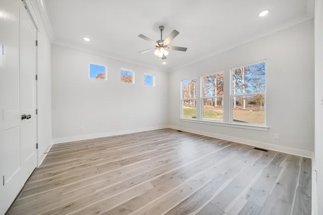 a view of an empty room with a window and wooden floor
