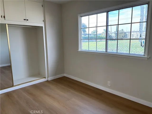 an empty room with wooden floor and cabinet